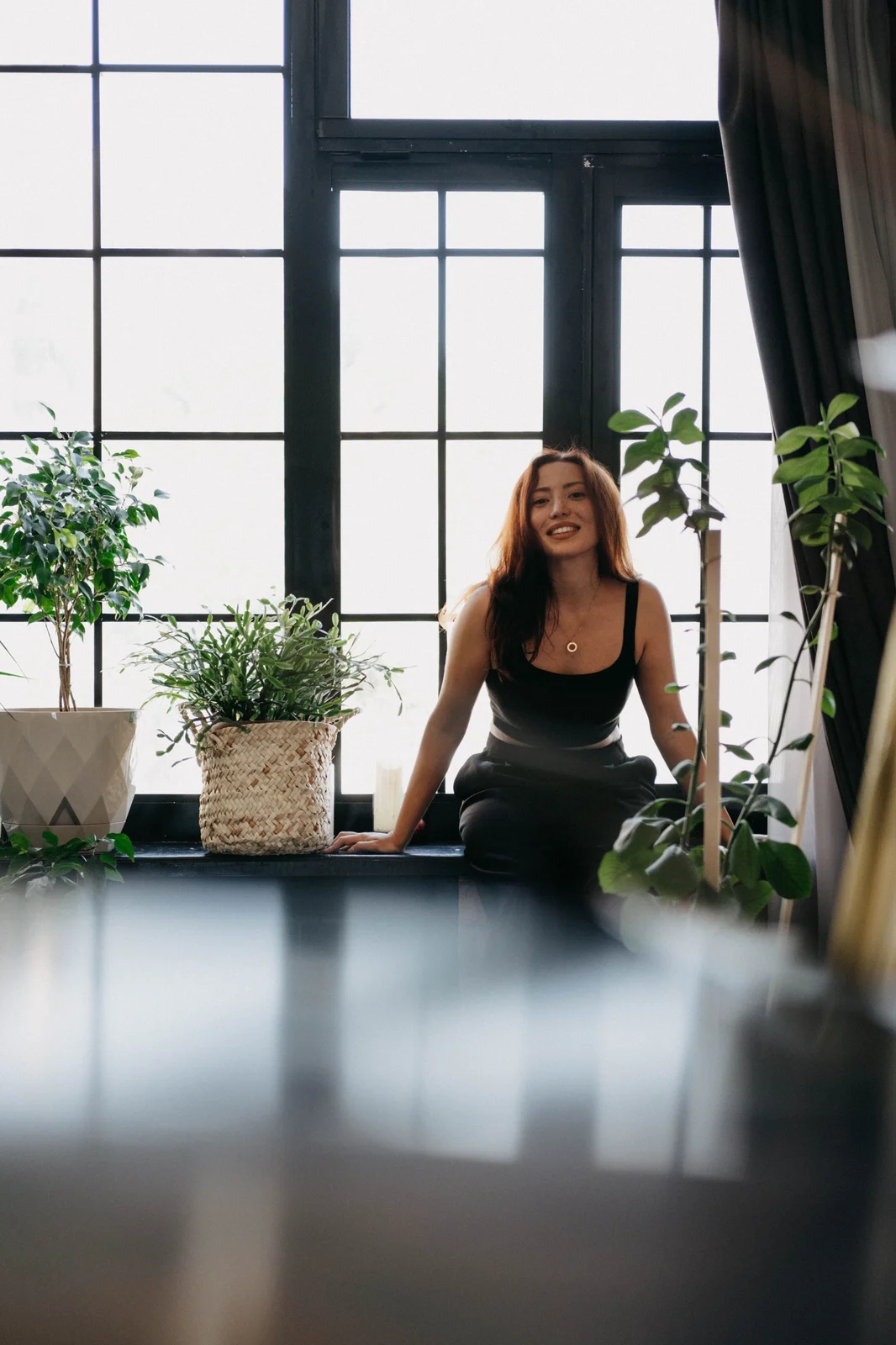 Uitgeruste medewerker zit ontspannen bij het raam tussen de planten